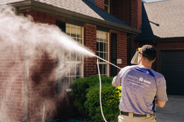 Window Genie tech pressure washing a brick home