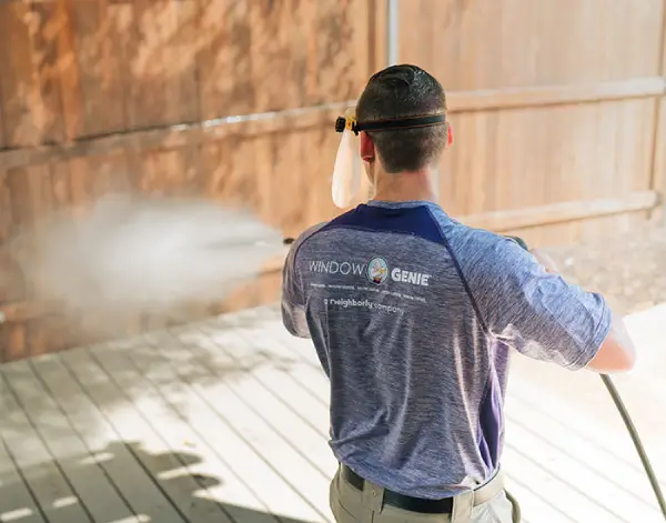 Technician pressure washing a wood fence.