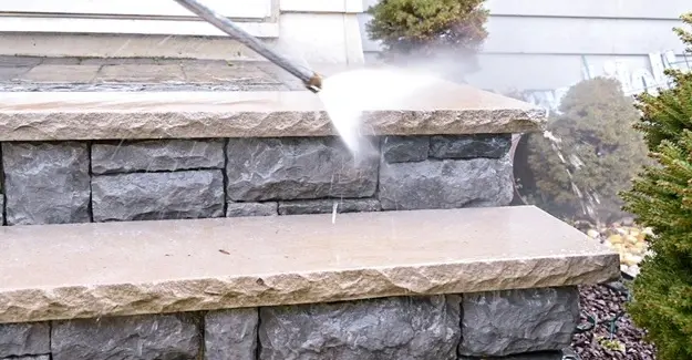 A pressure washer being used to clean a wood deck.