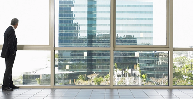 Man looking out the windows of a commercial building.