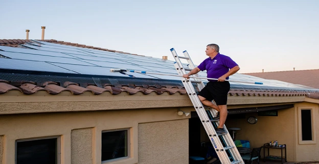 Window Genie tech cleaning solar panels on a home.