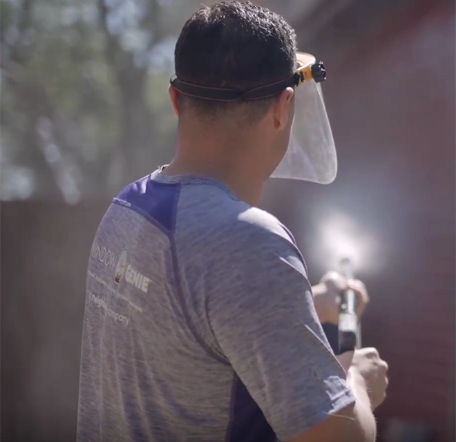 Window Genie service professional power washing the siding of a building.