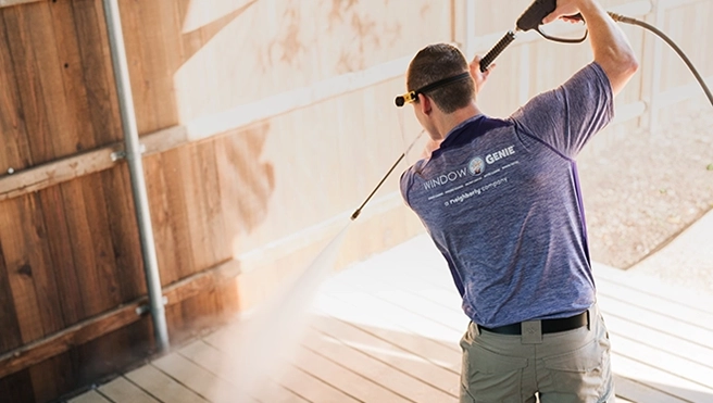 Window Genie service professional pressure washing a wood fence.