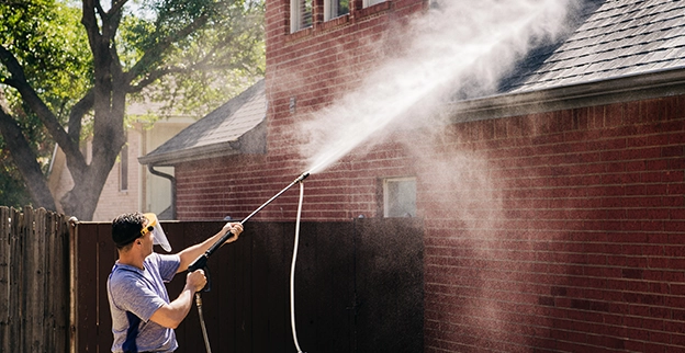 Window Genie service professional washing the roof of a single-family home.