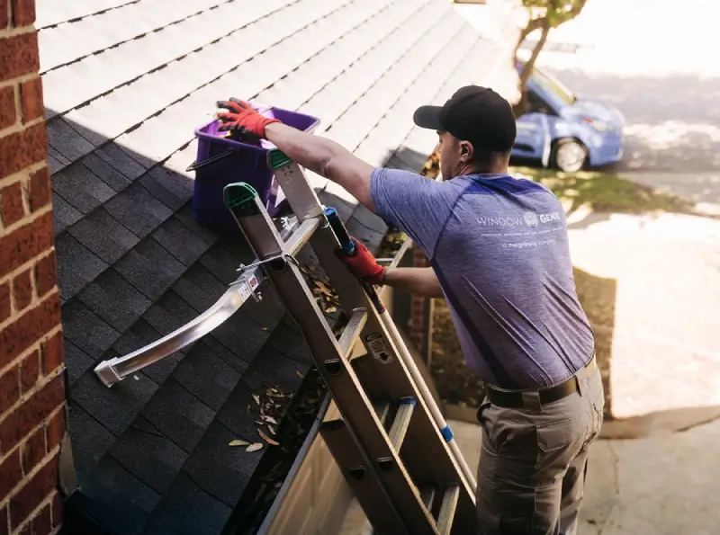 Window Genie professional cleaning gutters at a home.