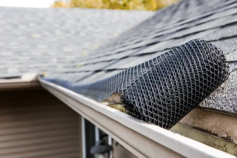 Roll of plastic mesh guard over gutter on a roof.