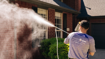 Window Genie professional pressure washing a brick house.