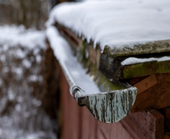 Snow covered roof with ice in the gutter.