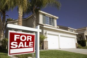 A house with a 'For Sale' sign displayed in front.