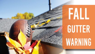 A rugby ball stuck in the gutter on the roof of a house.