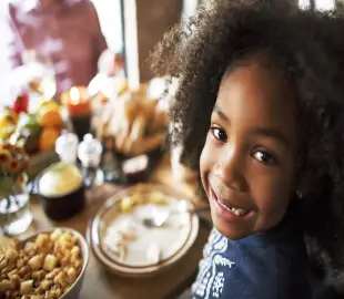 A happy little girl sitting at dining table.