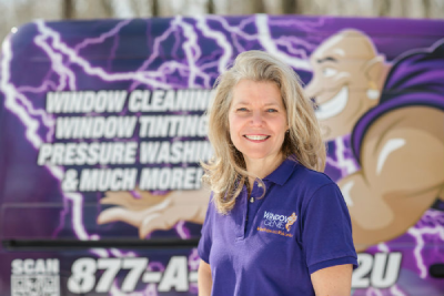 Smiling Window Genie professional in front of an advertisement board