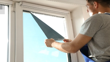 Technician installing a window film over an existing window.