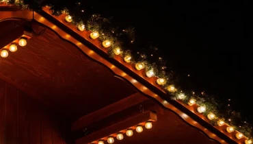 Christmas lights and garland hanging on the roof of a house.