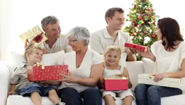 A family sitting on a couch exchanging presents.